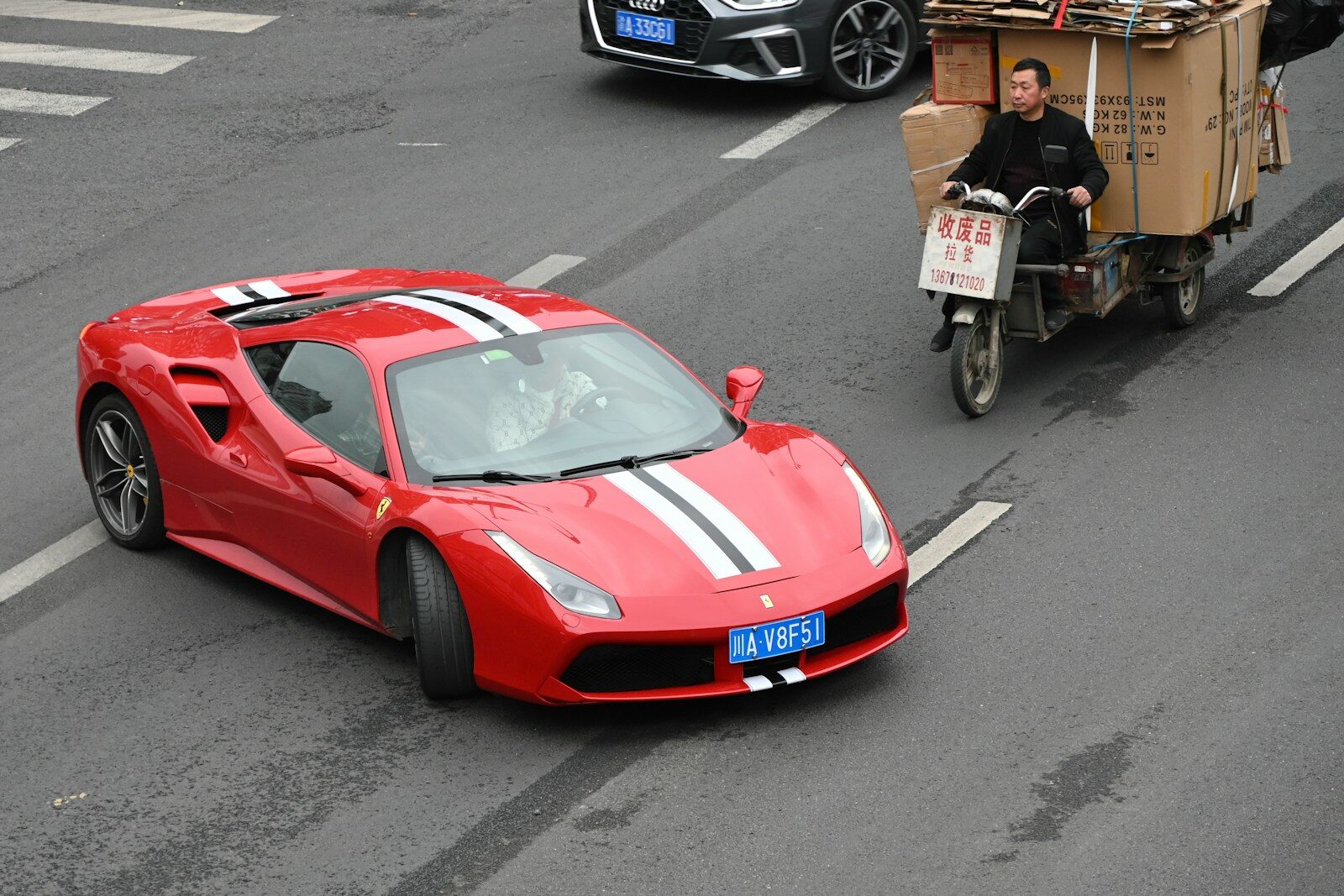 Red ferrari driving on a street with other vehicles.