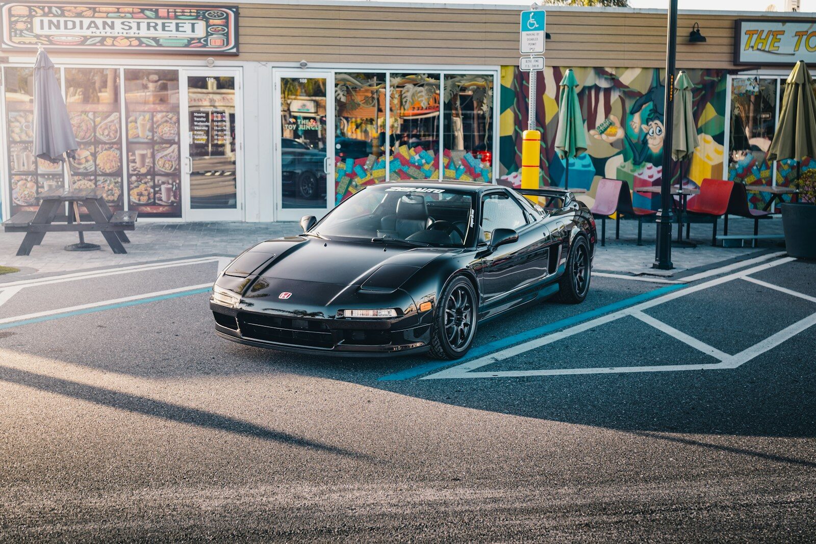 A black sports car parked in front of a store