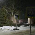 A street sign on a snowy street at night