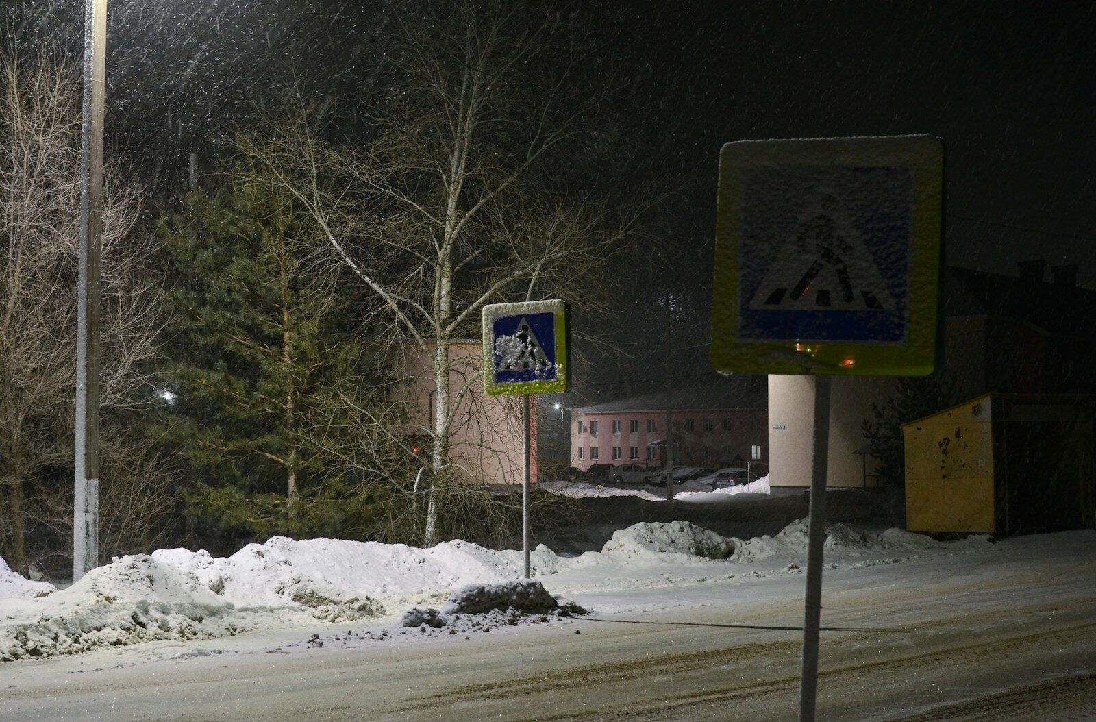 A street sign on a snowy street at night