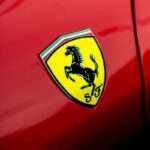 Ferrari Teases Retro-Inspired Supercar Reveal for July 4 Amid Manual Transmission Speculation a close up of a ferrari badge on a red car