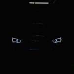 black car in the dark with lighted daytime running lights