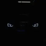 black car in the dark with lighted daytime running lights
