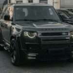 A black land rover defender is parked.
