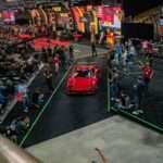 Red sports car drives through auction crowd