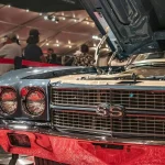 Classic blue car with hood open at an exhibition.