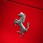 Ferrari prancing horse badge on a red hood, representative image for Ferrari's modern V-12 hypercar lineage