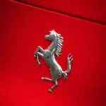 Ferrari prancing horse badge on a red hood, representative image for Ferrari's modern V-12 hypercar lineage