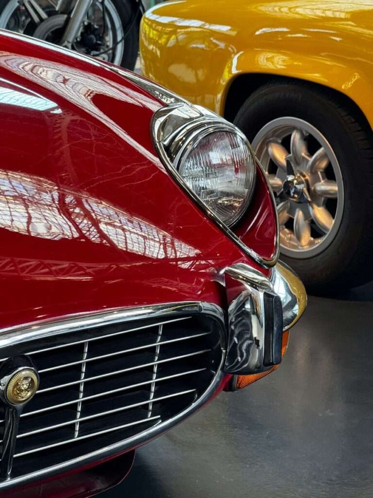 Close-up of a classic British sports car's chrome grille and headlight, evoking the era of the Aston Martin DB4's engineering