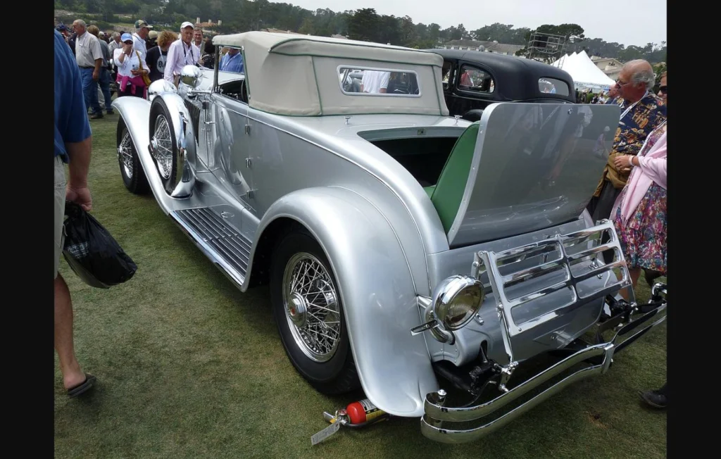 A silver 1929 Duesenberg Model J Murphy convertible coupe on display at a concours car show, front three-quarter view