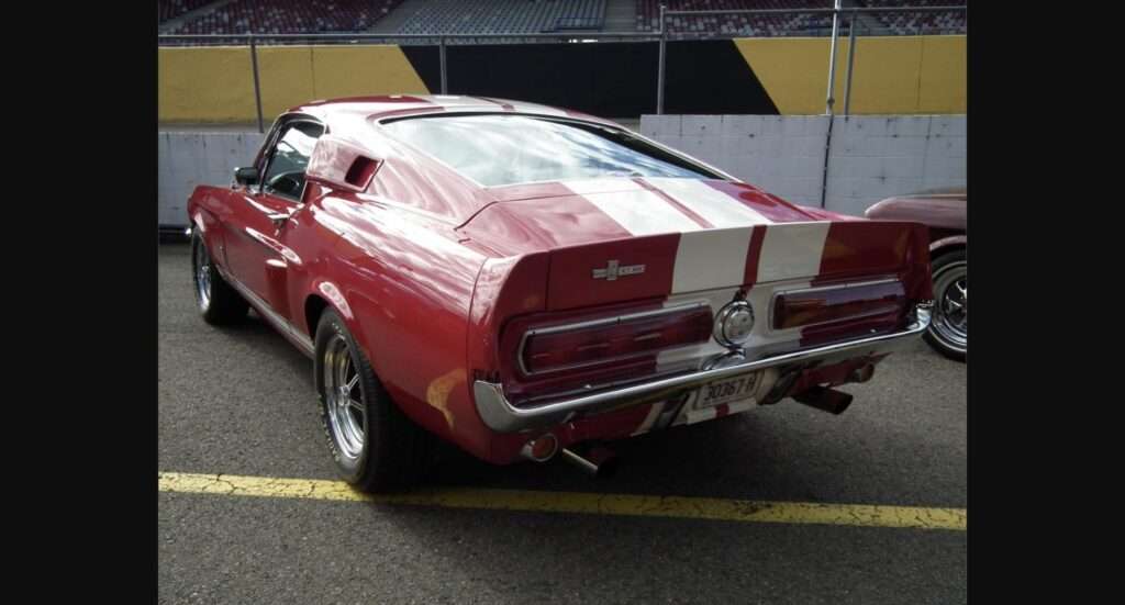 Rear three-quarter view of a red 1967 Shelby GT500 fastback with white stripes