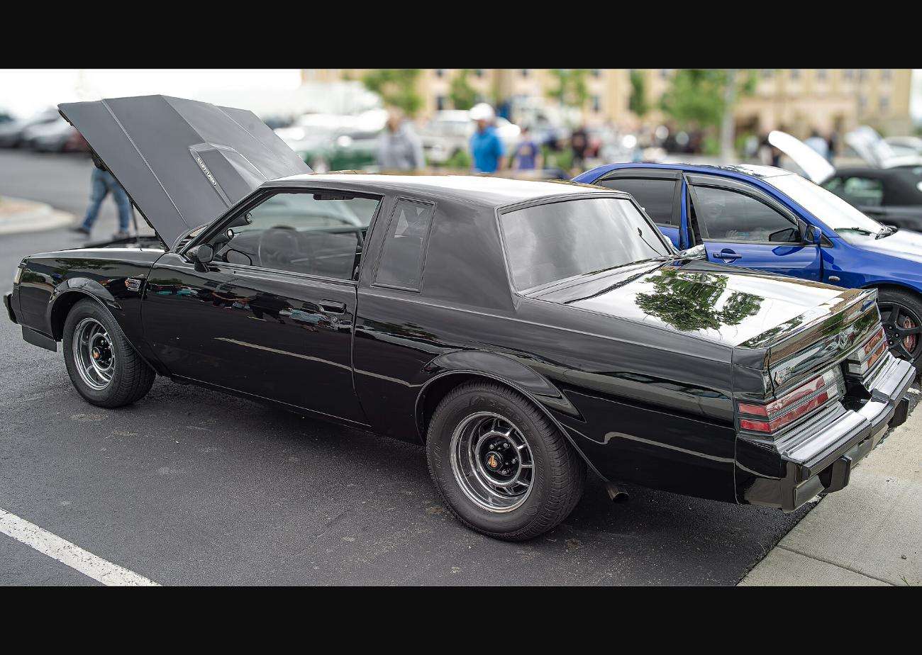 Black 1987 Buick Regal Grand National rear quarter view with hood open, showing chrome bumpers and standard Grand National wheels