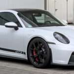 White Porsche 911 GT3 (992) coupe with swan-neck rear wing, front three-quarter view