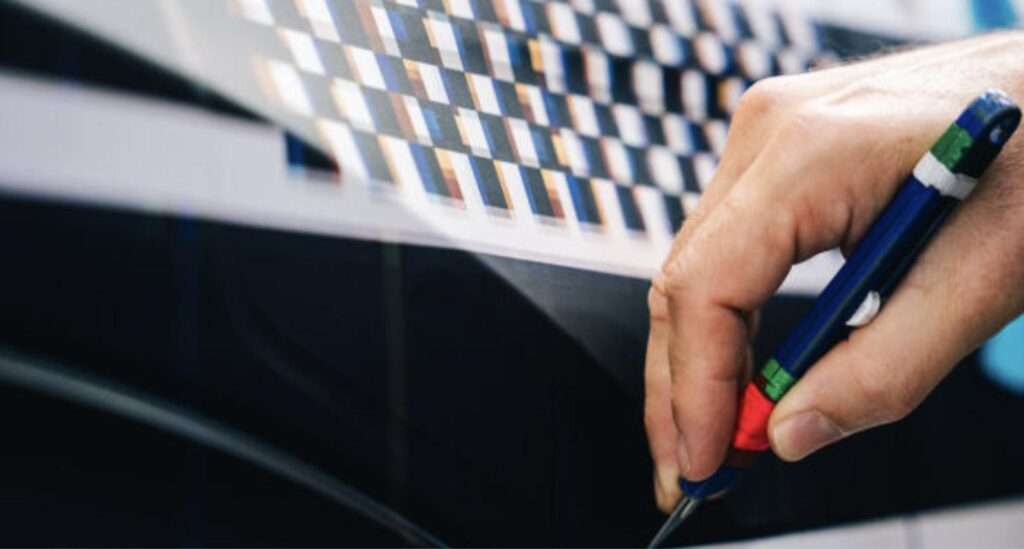 A technician hand-trims the vinyl design surface on Alpine's one-off A390, confirming the treatment is applied graphics rather than paint
