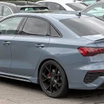 Current-generation Audi RS 3 sedan in gray, rear three-quarter view