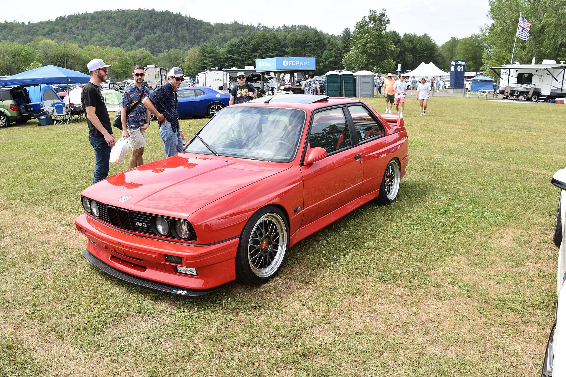Red 1990 BMW coupe with box-flared fenders at a car show