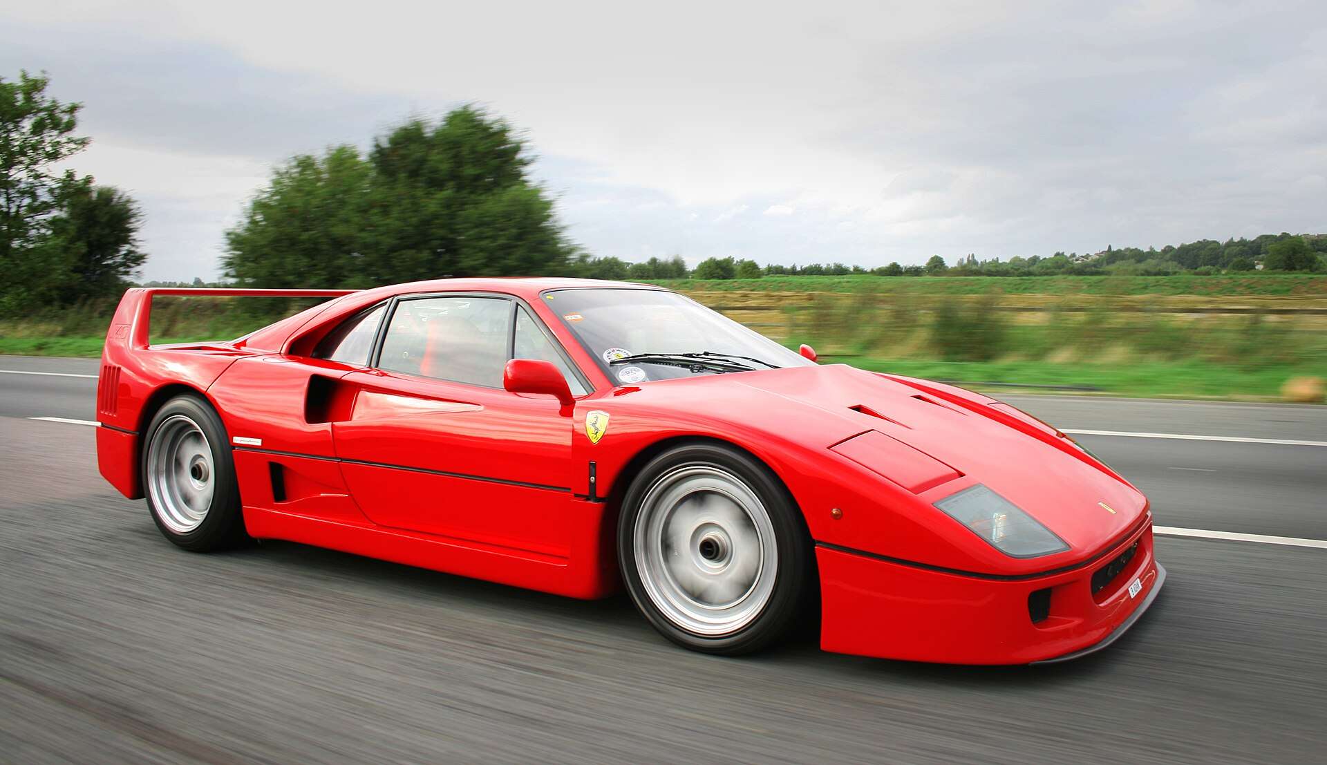 Red Ferrari F40 being driven on a public road