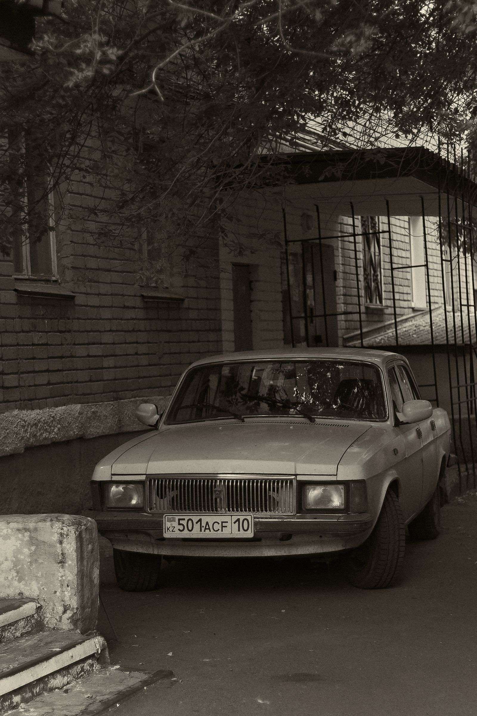 Weathered vintage sedan parked beside a brick wall