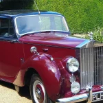 red vintage car on green grass field during daytime