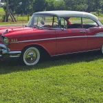 Red and white 1957 Chevrolet Bel Air front three-quarter view on grass