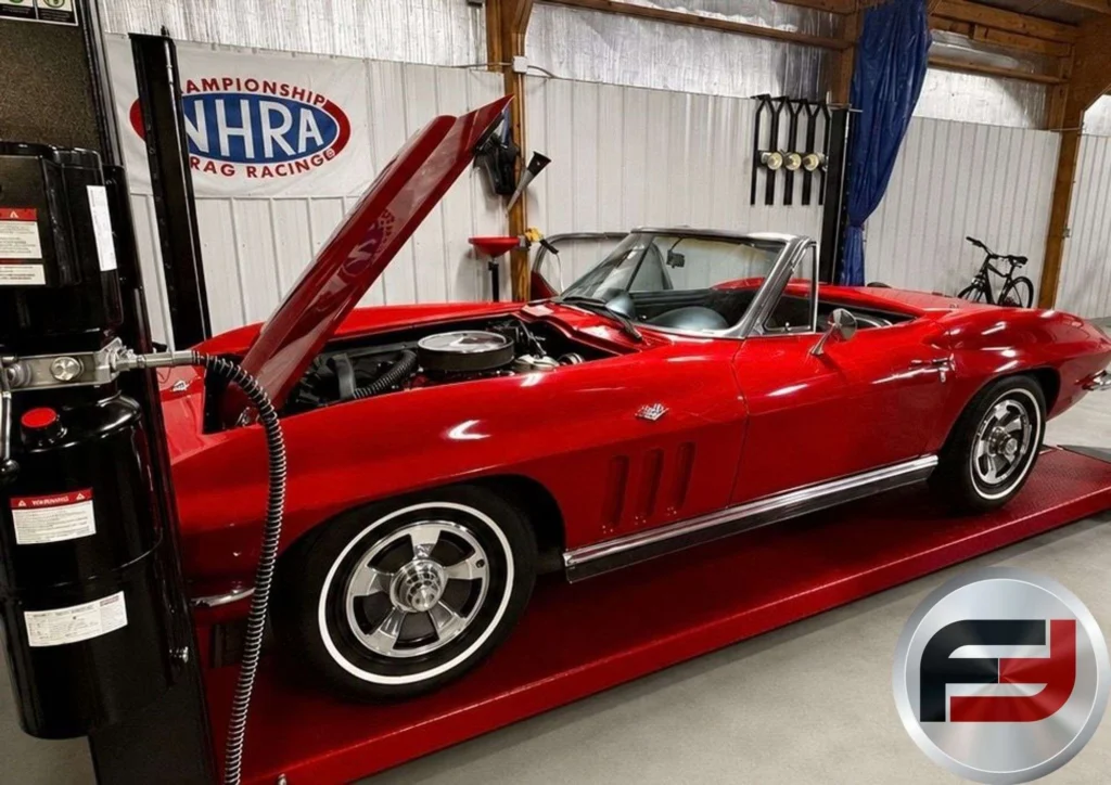 Red 1966 Chevrolet Corvette convertible on a lift with the hood open