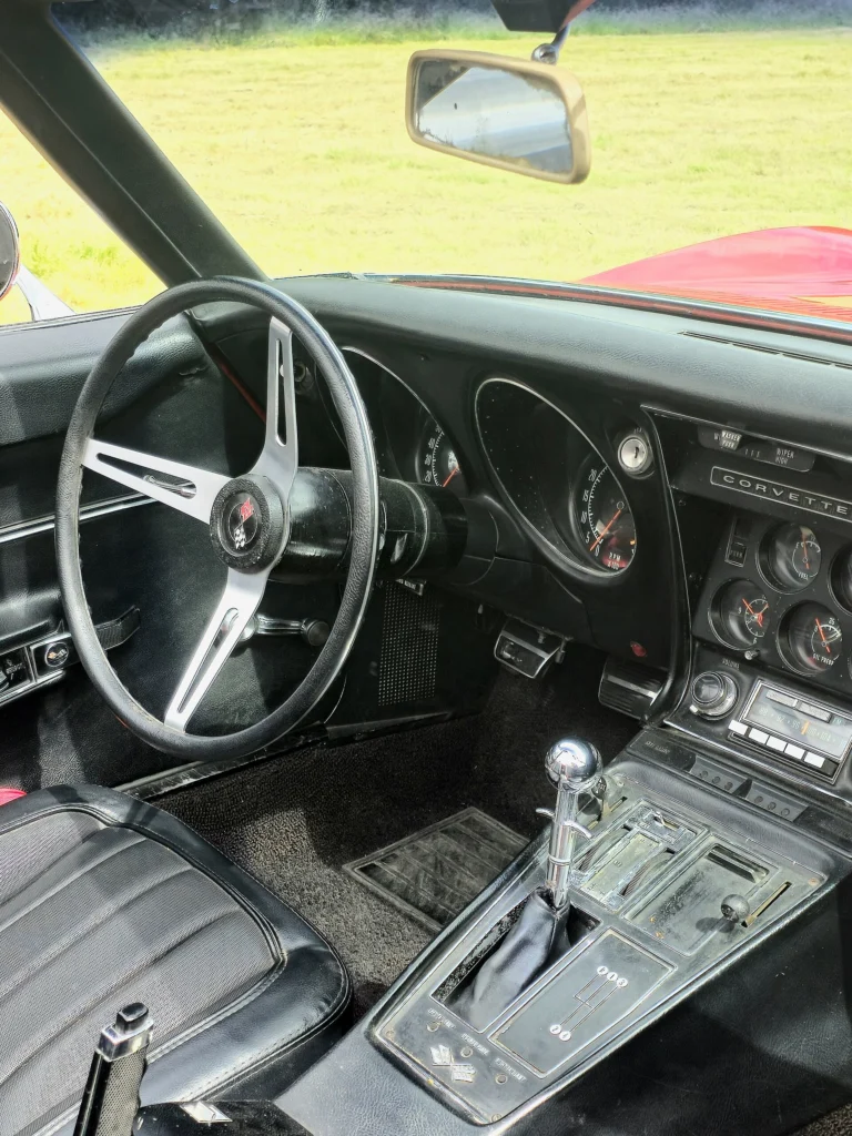 Interior of a 1968 Chevrolet Corvette C3 with black vinyl bucket seats, three-spoke wheel and automatic console