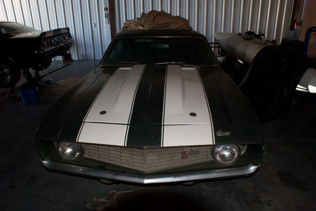 A dark green 1969 Camaro Z/28 with white hood stripes stored in a metal garage