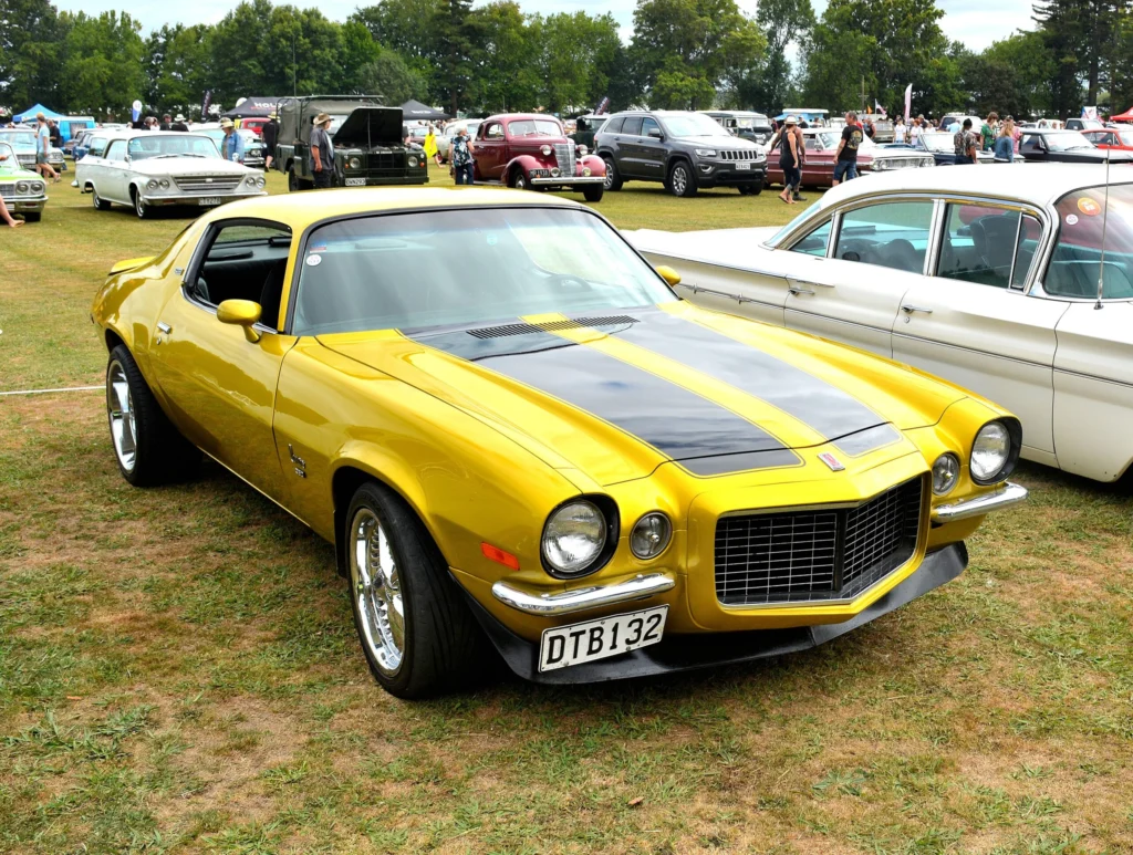 Yellow 1971 Chevrolet Camaro Z28 with black hood stripes at an outdoor car show