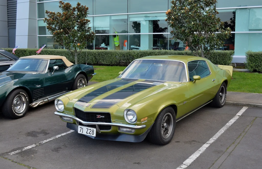 Lime green 1973 Chevrolet Camaro Z28 with black hood and stripe graphics parked in a lot