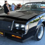 Buick GNX (1987): Collector Spec Sheet Black 1987 Buick GNX with fender louvers and black mesh wheels, front three-quarter view
