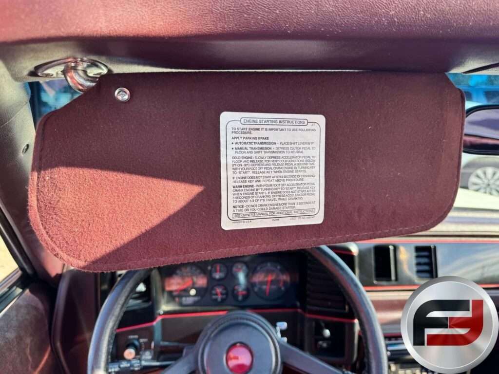Driver sun visor with factory label above the gauges in the 1987 Monte Carlo SS