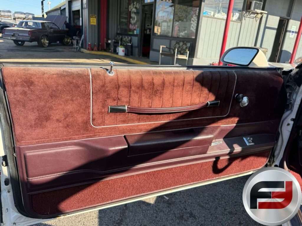 Driver door panel with maroon trim and power window switches in the 1987 Monte Carlo SS