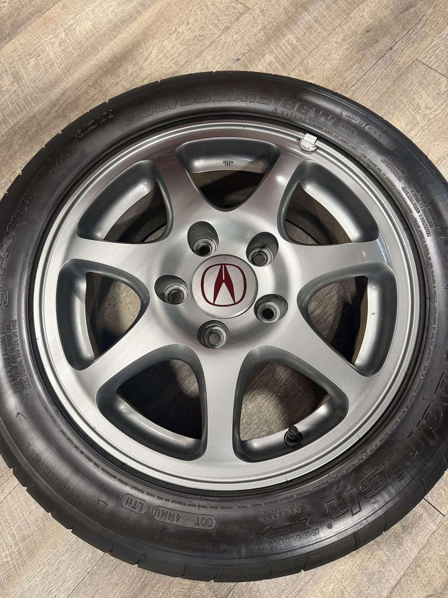 Seven-spoke 15-inch alloy wheel with five lug holes and Acura center cap from a 2000 Integra Type R