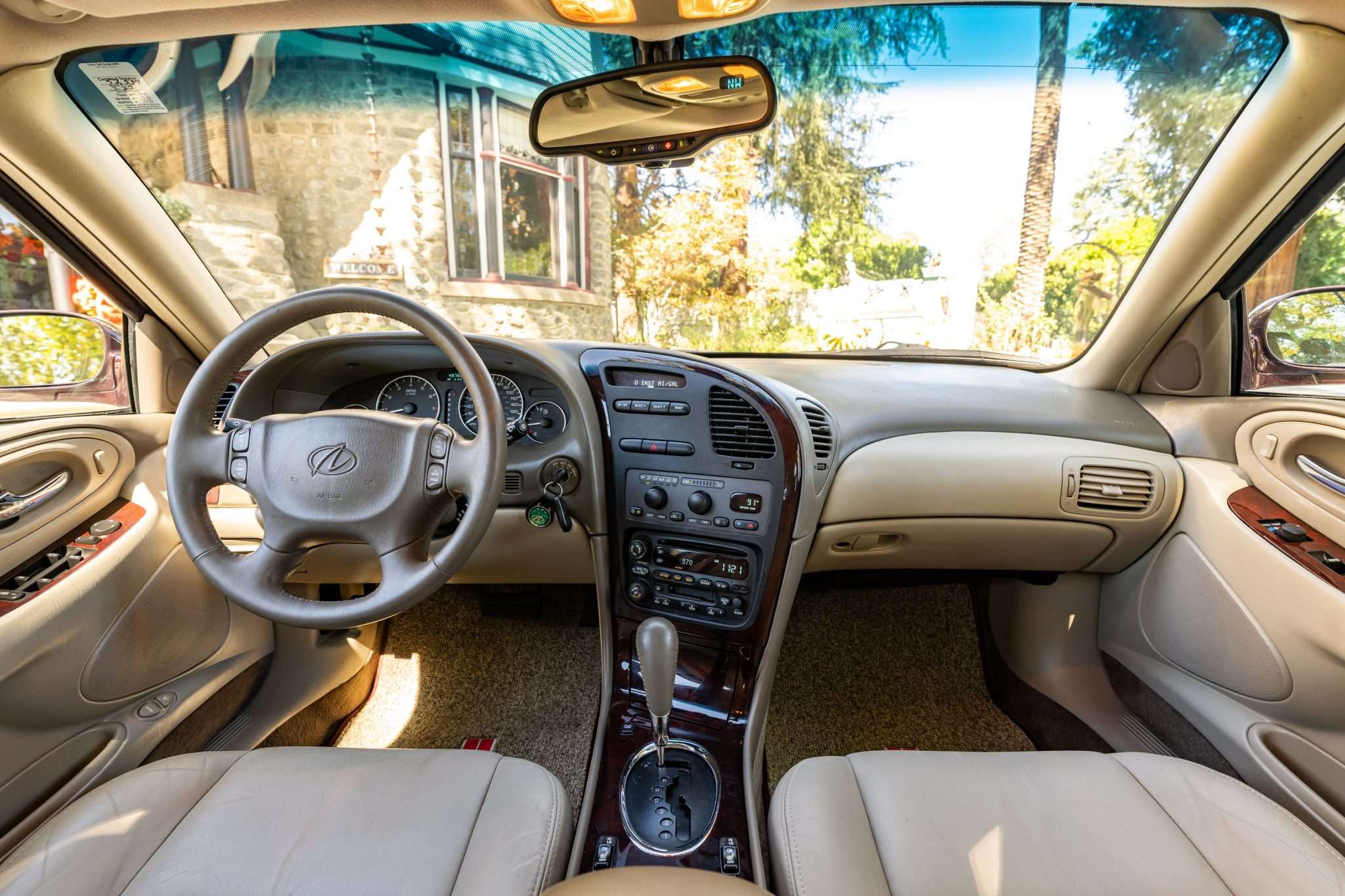 Front interior of a 2003 Oldsmobile Aurora Final 500 with Neutral leather seats, burled wood trim and leather steering wheel