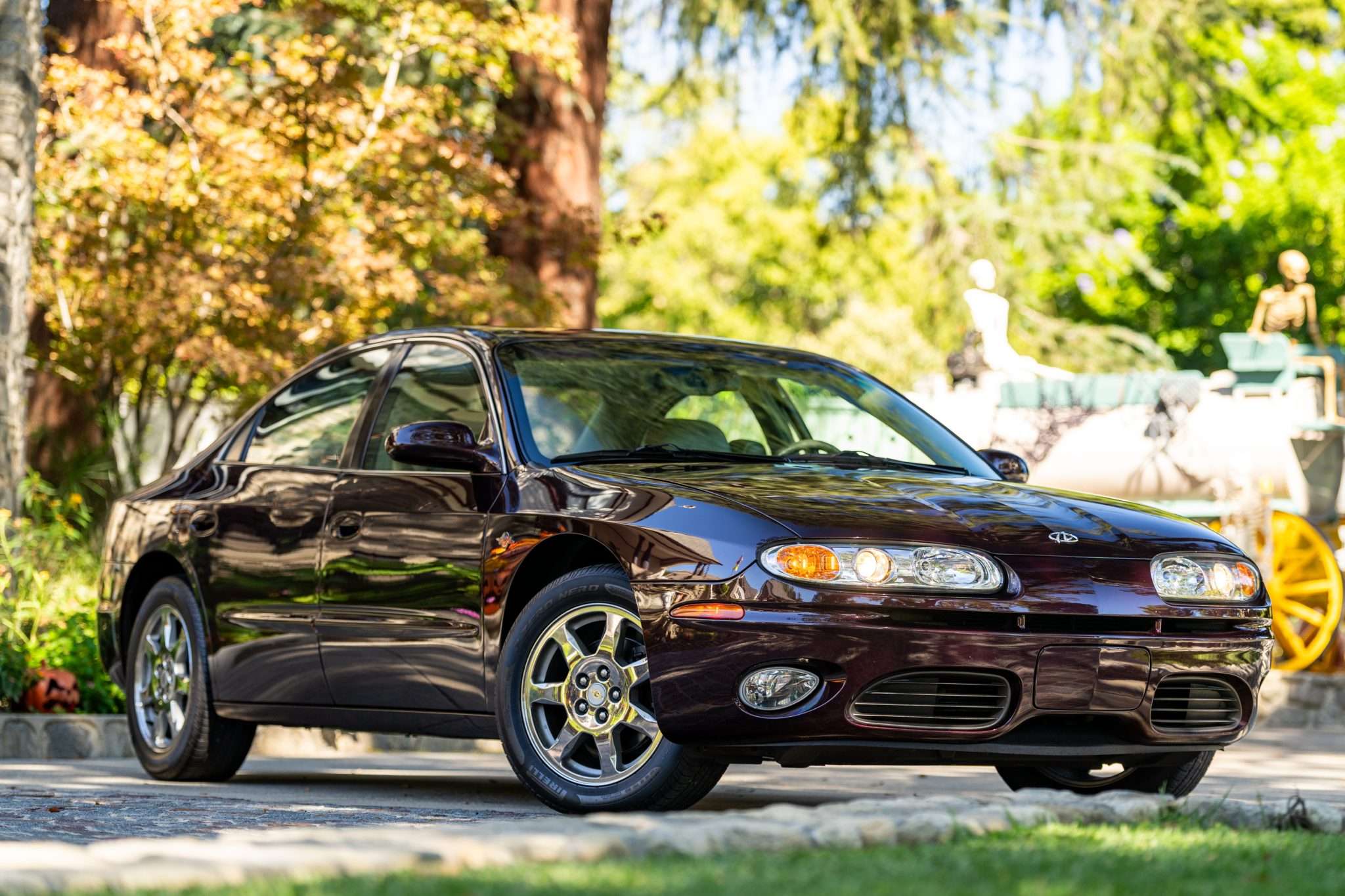 Rear three-quarter view of a Dark Cherry Metallic 2003 Oldsmobile Aurora Final 500 Edition sedan with chrome wheels