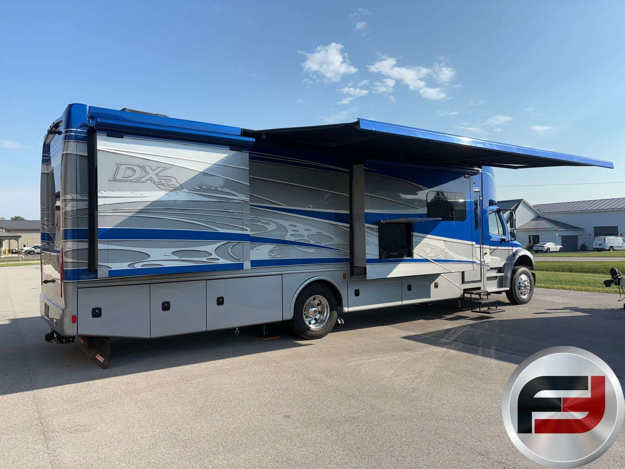 Passenger-side view of the 2017 Dynamax DX3 37TS with awning and slide-outs deployed
