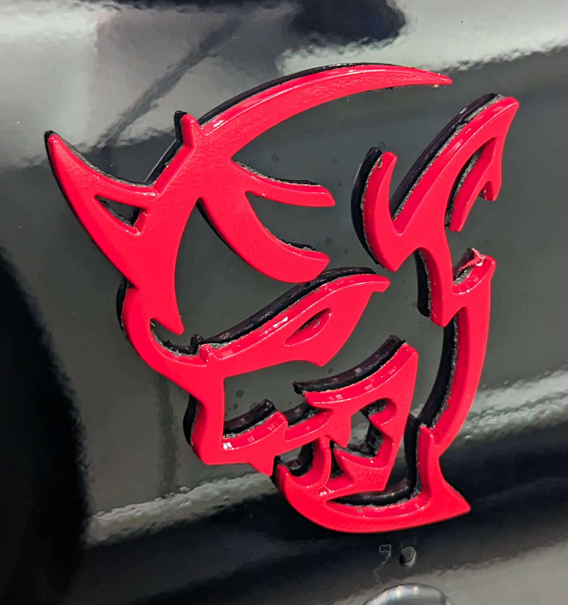 Close-up of the red Demon head badge on the black fender of a Dodge Challenger SRT Demon