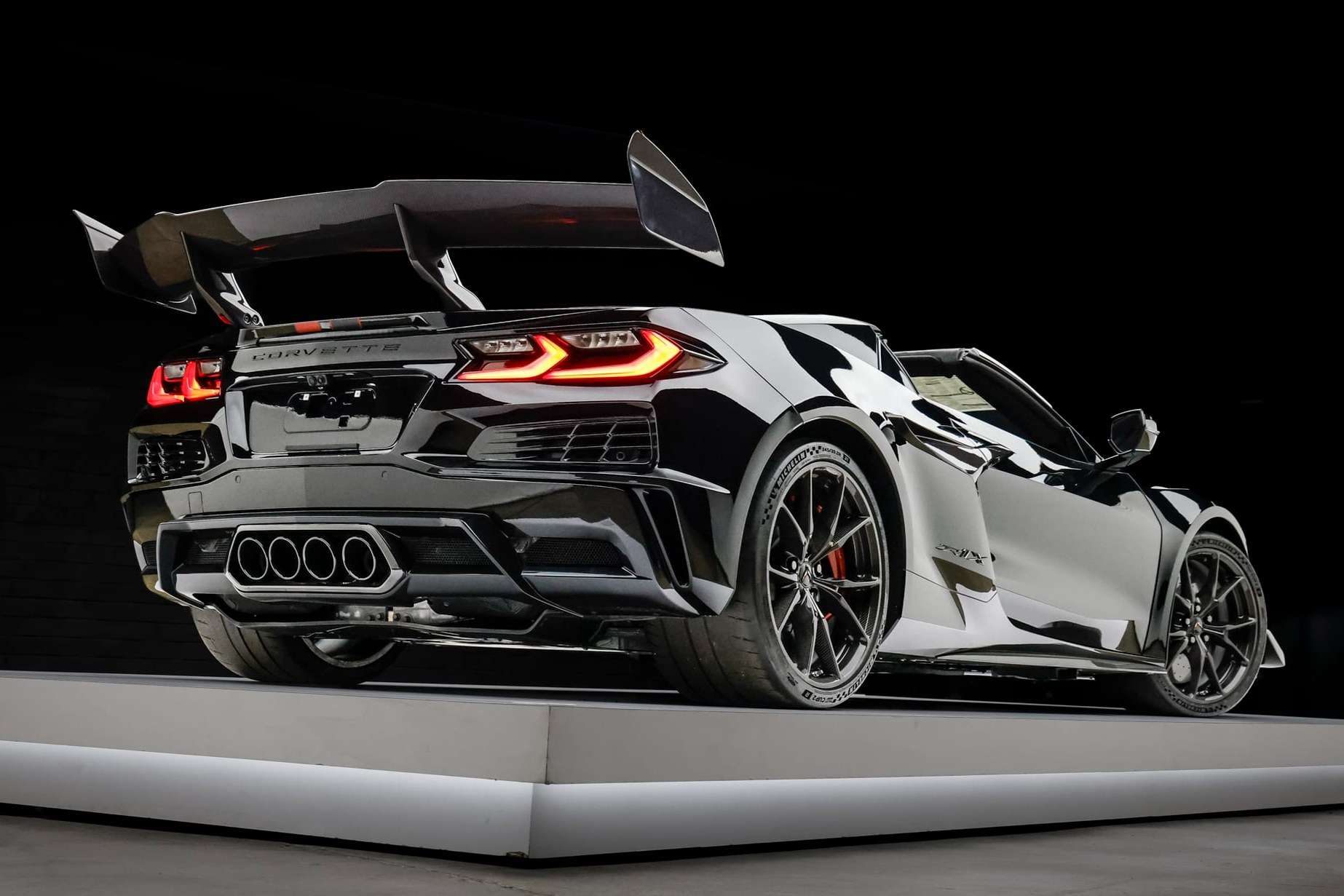 Rear three-quarter of a black 2027 Chevrolet Corvette ZR1X convertible with the Carbon Fiber Aero Package and tall rear wing