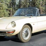 1966 Alfa Romeo 1600 Spider Duetto in Ivory, seen from the front three-quarter with the round tail, chrome bumpers and steel wheels