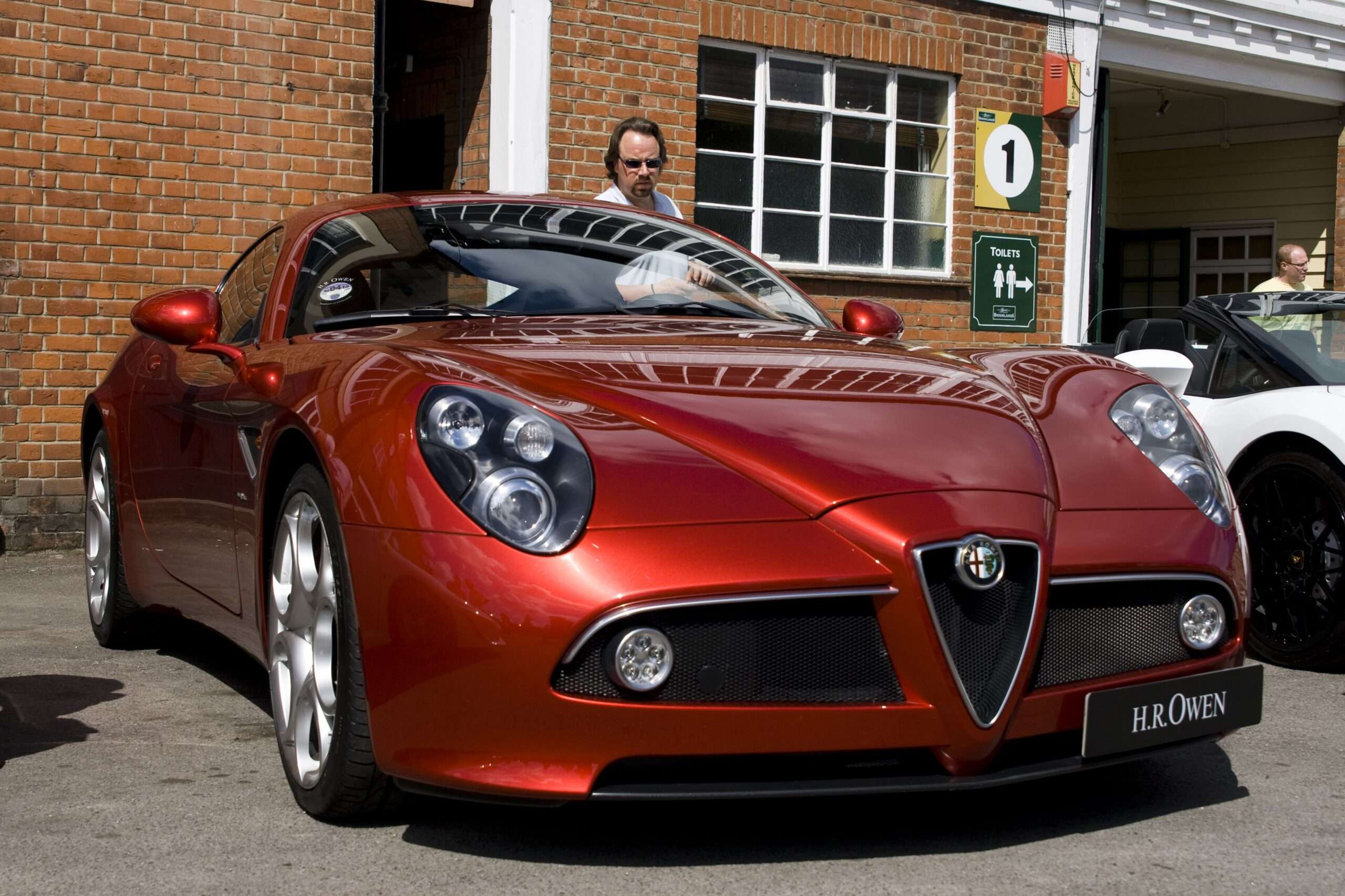 Front three-quarter view of a red Alfa Romeo 8C Competizione with the Alfa Romeo shield grille and round headlights