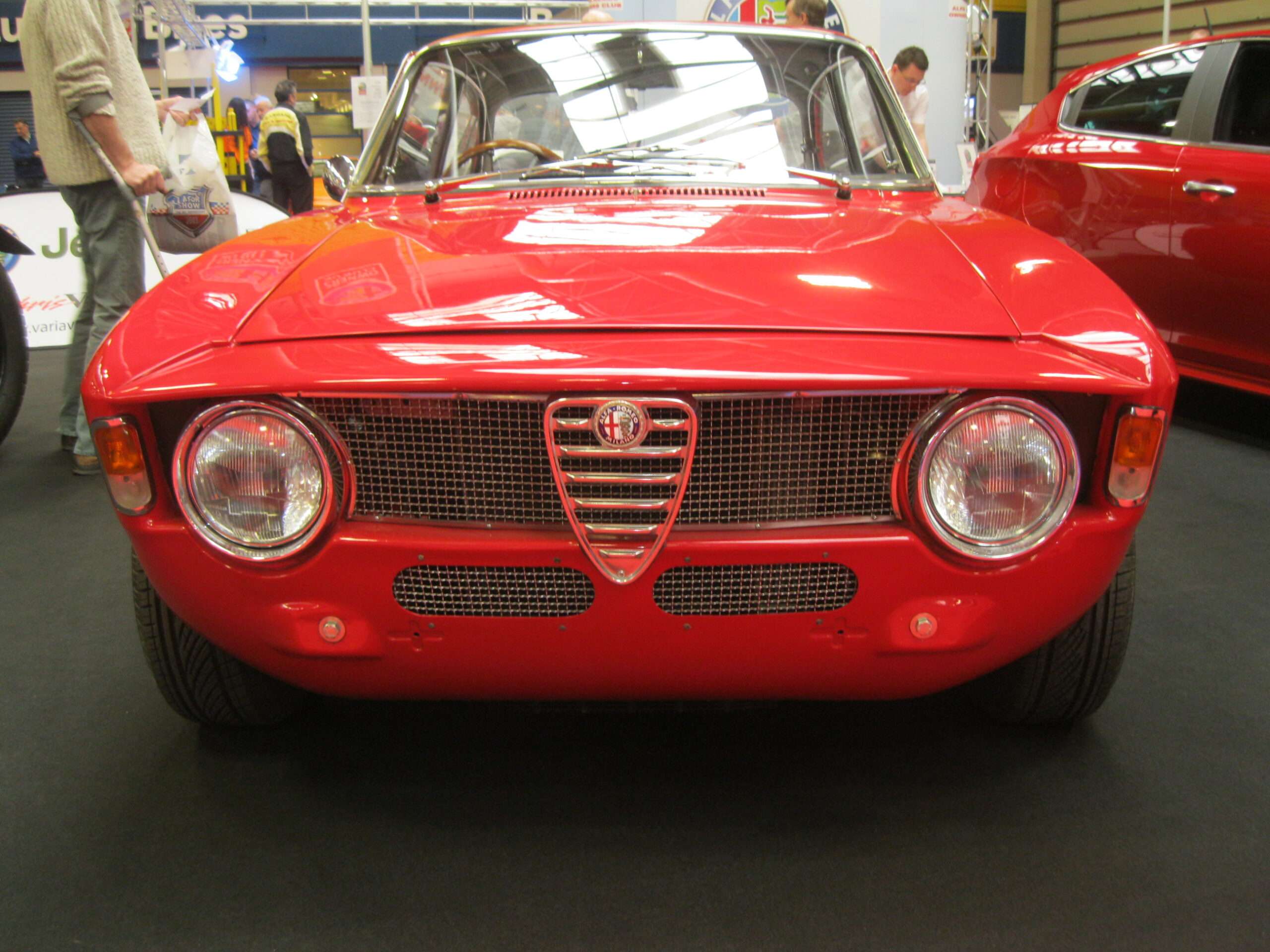Front of a red 1966 Alfa Romeo Giulia Sprint GTA showing the shield grille, round headlights and bonnet