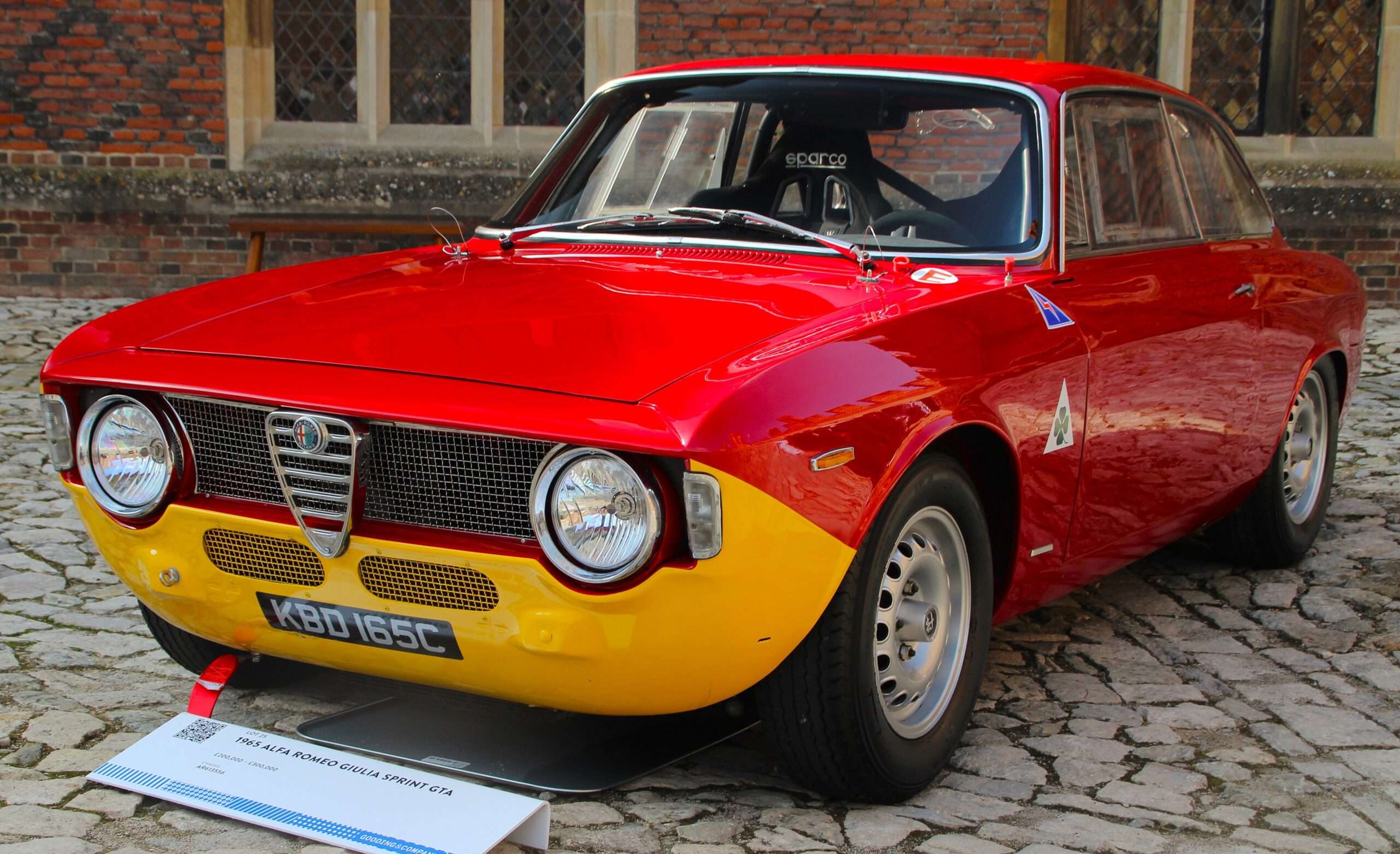 Red 1965 Alfa Romeo Giulia Sprint GTA with yellow lower nose, front view on cobbles at a concours
