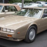 Front three-quarter view of a Pennine Sand 1988 Aston Martin Lagonda Series 4 showing the body-color grille surround and six fixed headlights