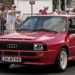 Red Audi Sport quattro short-wheelbase coupe driving past spectators at the Classic Days show in 2022