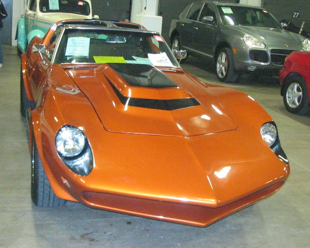 Orange Baldwin-Motion modified Corvette with an extended custom nose and hood inside an auction hall