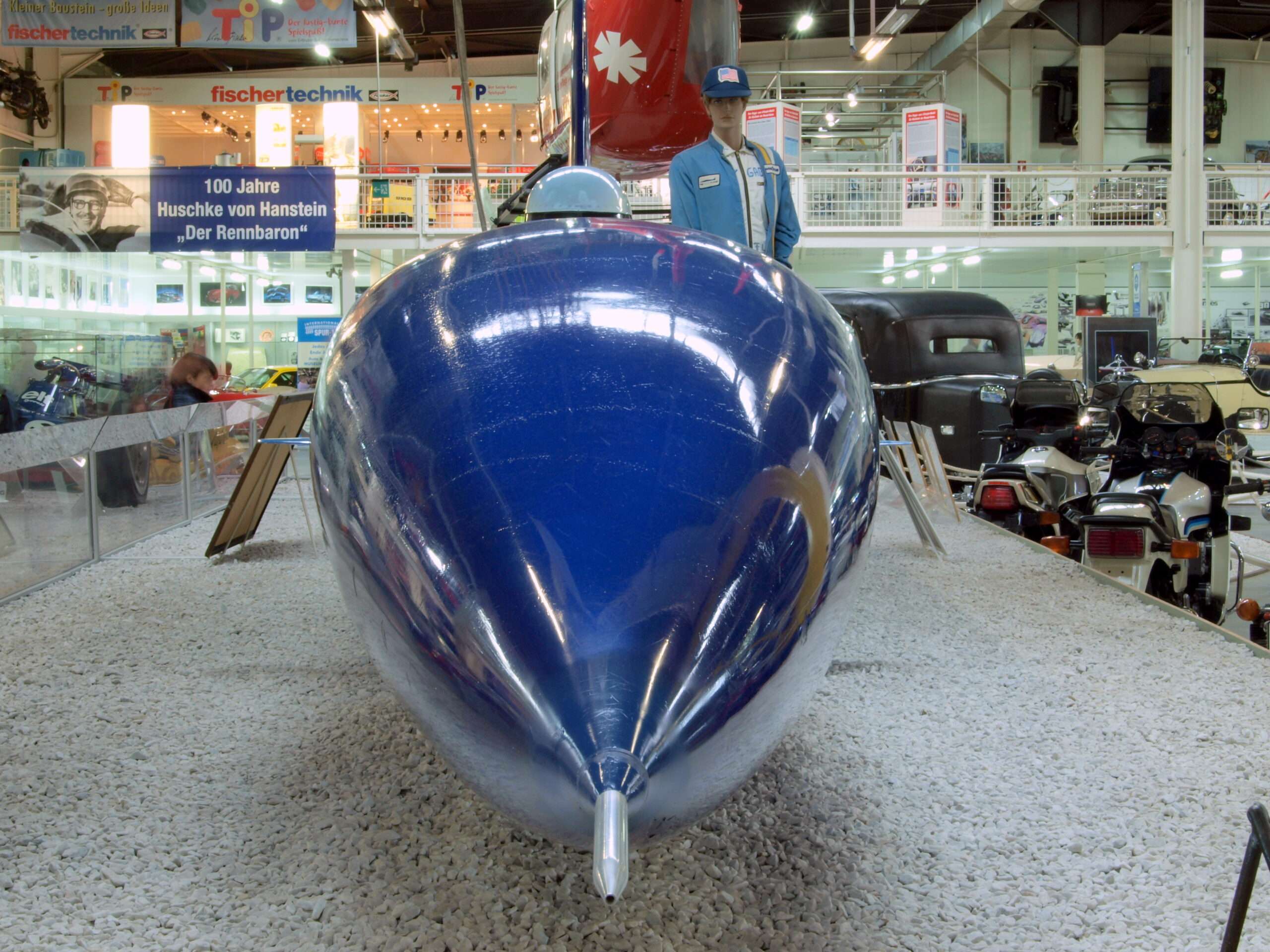 Front view of the Blue Flame rocket car, its blue nose cone tapering to a pointed tip, on display at the Auto & Technik Museum Sinsheim