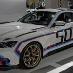 2023 BMW 3.0 CSL in Alpine White with BMW M tricolor stripes and gold center-lock wheels on display in Zurich