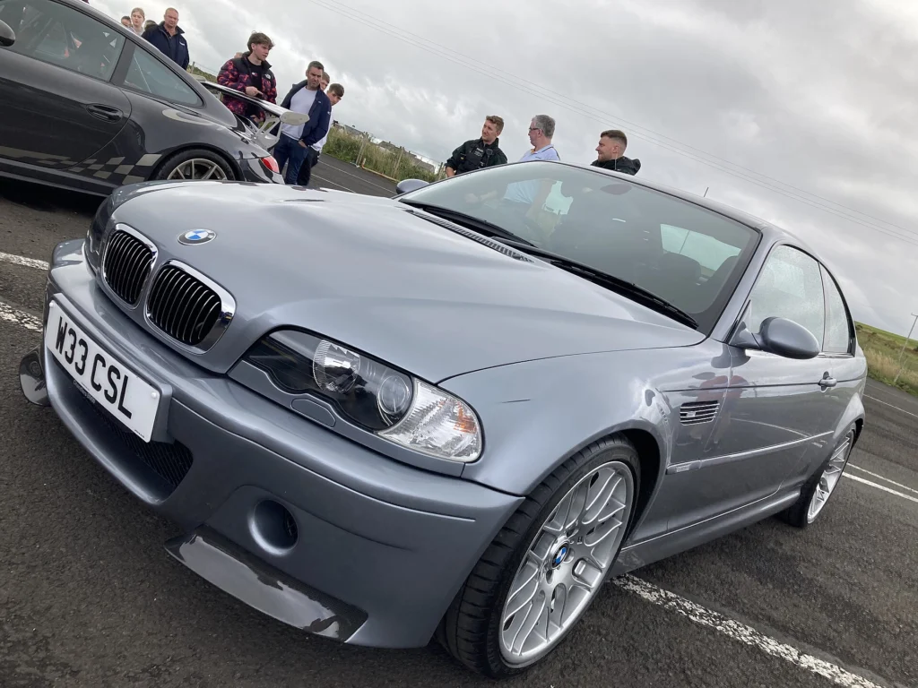 Front three-quarter view of a grey 2003 BMW E46 M3 CSL showing the front bumper and wheel