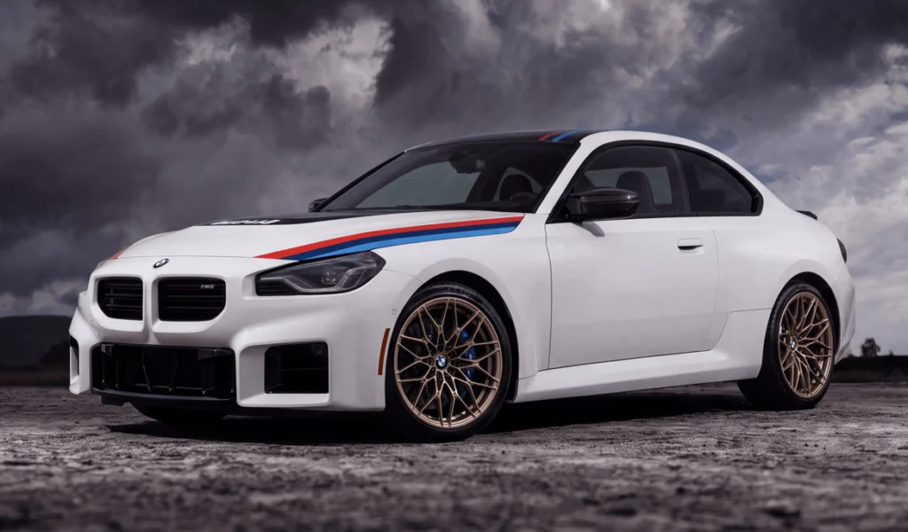 Alpine White 2026 BMW M2 Turbo Design Edition with BMW Motorsport stripes under stormy skies
