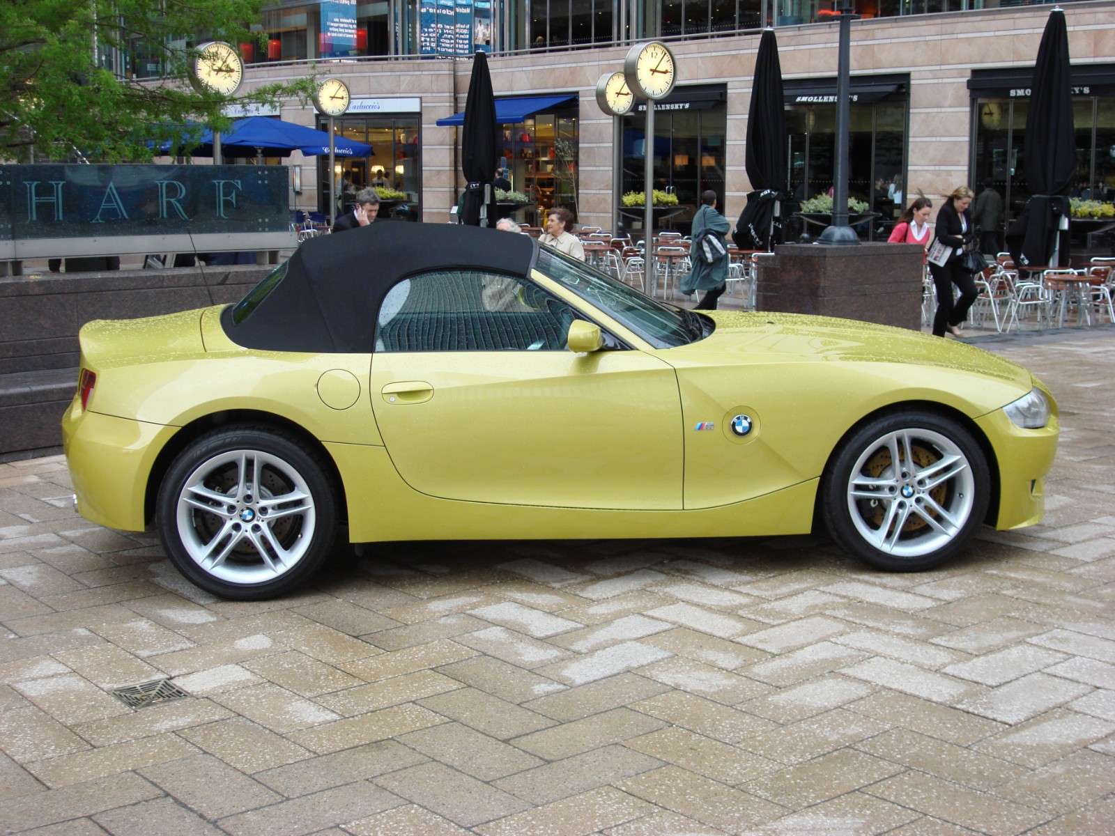 Side profile of a yellow BMW Z4 M Roadster with its black soft top raised and M-specific alloy wheels